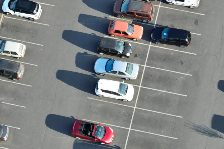 Luftaufnahme von mehreren geparkten Autos in verschiedenen Farben auf einem Parkplatz. günstiges Parken Warnemünde