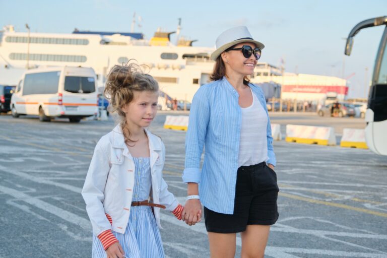 Mutter und Tochter gehen am Hafen entlang; Familienausflug ans Meer, Sommerurlaub. Seeverkehr, Fähre im Hafen im Hintergrund.